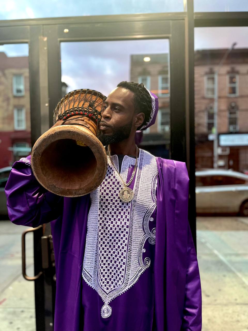 Prince Mohamed in royal purple robe holding a djembe drum